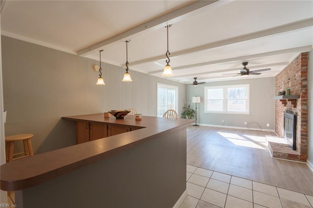 kitchen with light tile patterned floors, a fireplace, beam ceiling, and decorative light fixtures