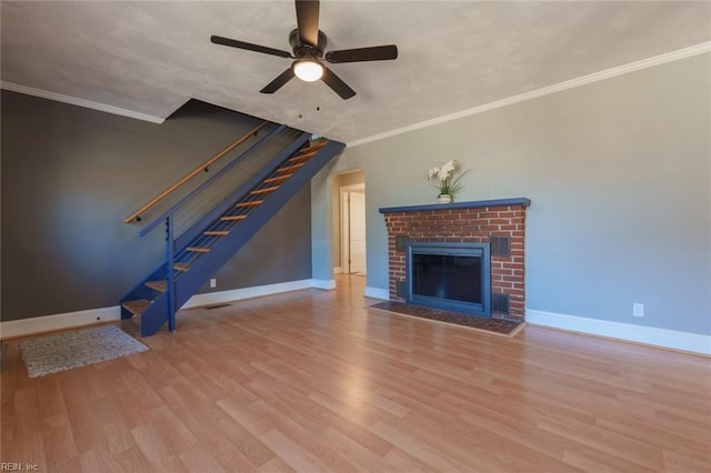 unfurnished living room with crown molding, ceiling fan, a fireplace, and light hardwood / wood-style flooring