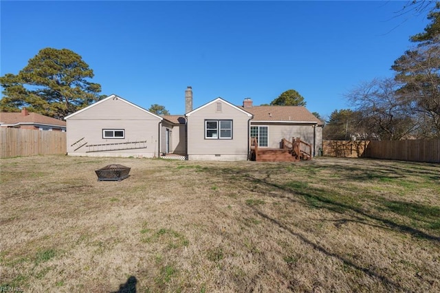 rear view of house featuring a fire pit and a lawn