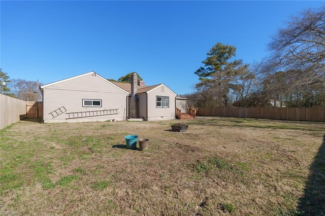 back of house with a lawn and an outdoor fire pit