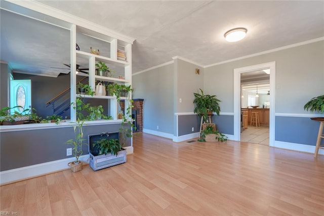 living room featuring a brick fireplace, ornamental molding, and light hardwood / wood-style floors