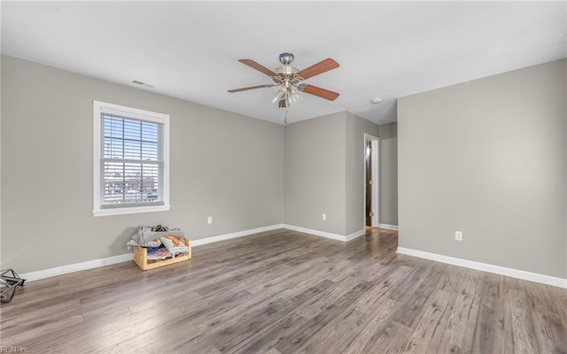 unfurnished room with ceiling fan, baseboards, and wood finished floors