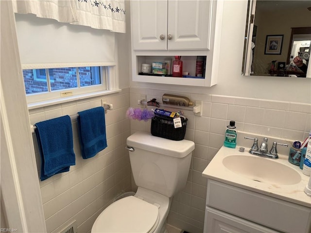 bathroom featuring vanity, toilet, and tile walls