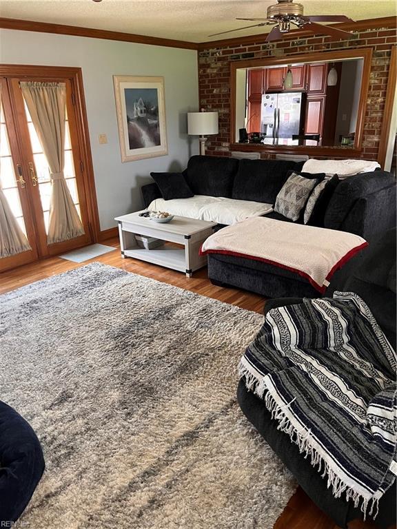 living room featuring crown molding, ceiling fan, a textured ceiling, and hardwood / wood-style flooring