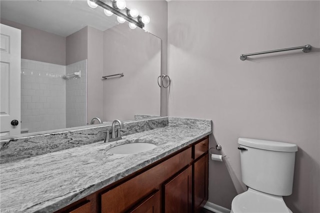 bathroom with vanity, toilet, and a tile shower