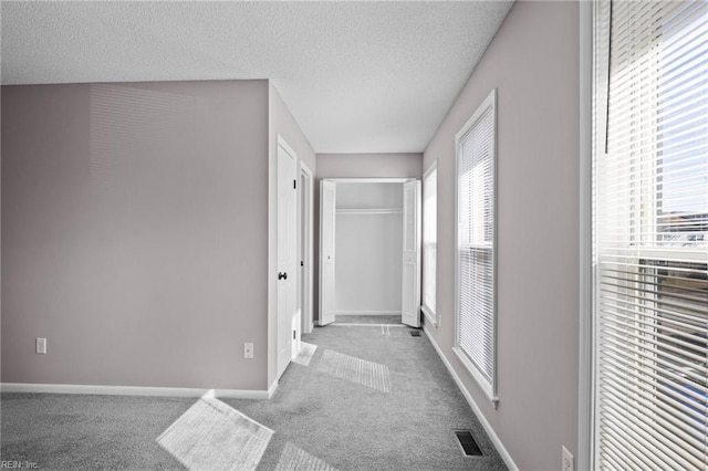 hallway featuring light colored carpet and a textured ceiling