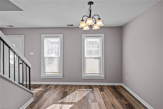 entryway featuring plenty of natural light, dark hardwood / wood-style floors, a notable chandelier, and a textured ceiling