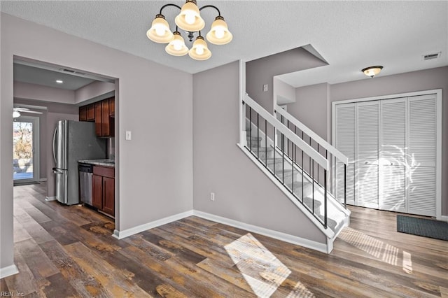 interior space featuring dark wood-type flooring, a chandelier, and a textured ceiling