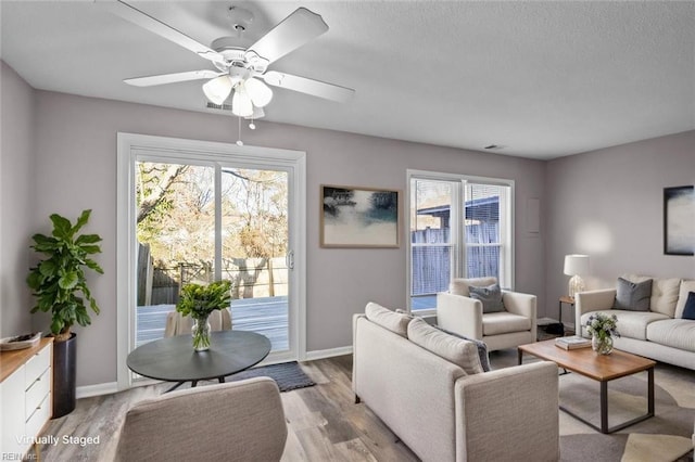 living room with a wealth of natural light, light hardwood / wood-style floors, and ceiling fan