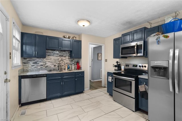 kitchen with appliances with stainless steel finishes, sink, blue cabinetry, and decorative backsplash