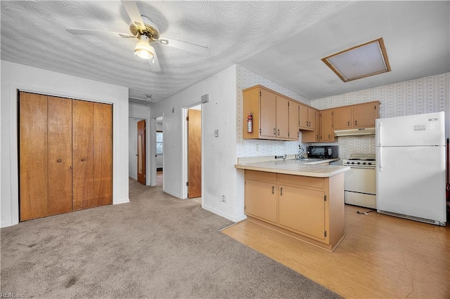 kitchen with gas stove, light carpet, kitchen peninsula, white fridge, and ceiling fan