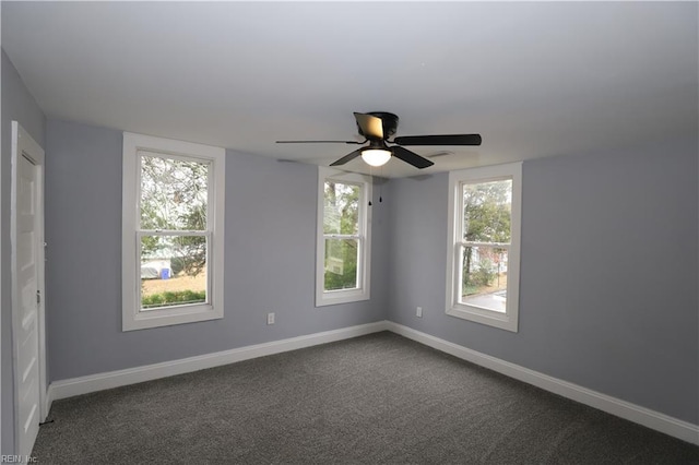 empty room featuring ceiling fan and dark colored carpet