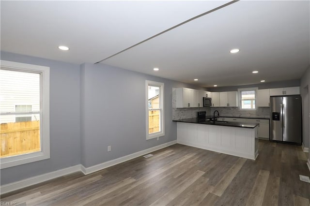 kitchen featuring appliances with stainless steel finishes, sink, white cabinets, decorative backsplash, and kitchen peninsula