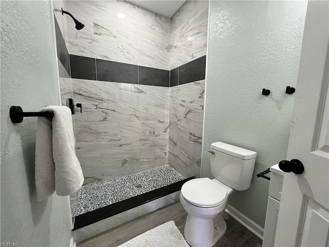 bathroom featuring a tile shower and toilet