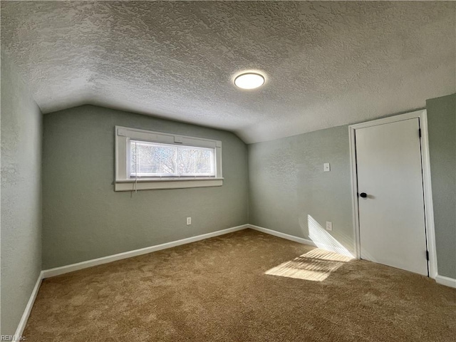 carpeted spare room featuring vaulted ceiling and a textured ceiling