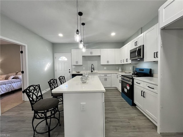 kitchen with white cabinetry, appliances with stainless steel finishes, a center island, and pendant lighting