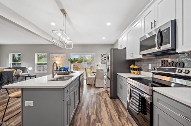 kitchen featuring appliances with stainless steel finishes, sink, pendant lighting, and white cabinets