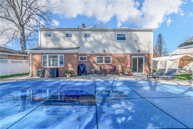 back of property featuring a patio, brick siding, fence, and a fenced in pool