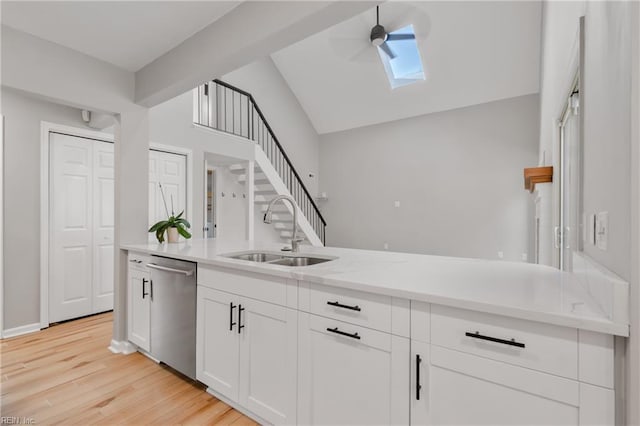 kitchen featuring white cabinetry, light wood-type flooring, sink, lofted ceiling with skylight, and stainless steel dishwasher