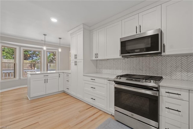 kitchen with pendant lighting, crown molding, stainless steel appliances, white cabinets, and tasteful backsplash