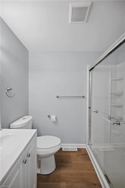bathroom with wood-type flooring, toilet, vanity, and walk in shower