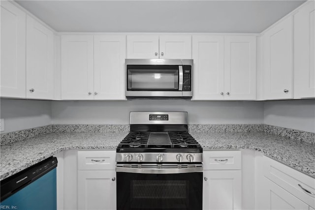 kitchen with stainless steel appliances, white cabinetry, and light stone counters