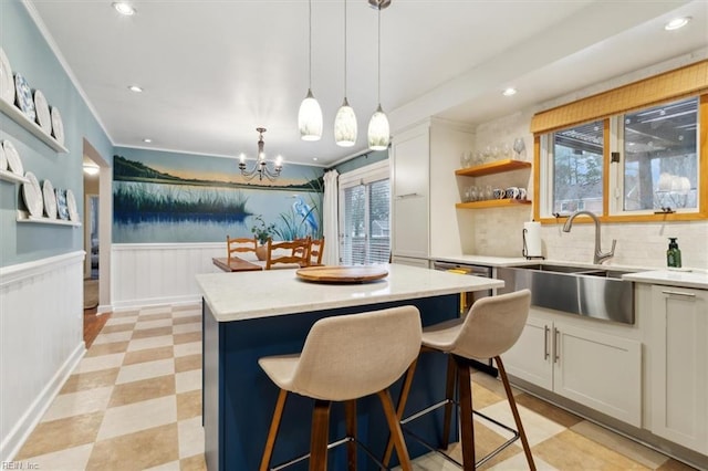 kitchen with hanging light fixtures, a center island, sink, and white cabinets