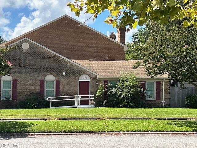 ranch-style house featuring brick siding, a chimney, and a front lawn