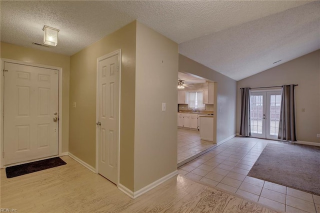 tiled foyer with lofted ceiling, french doors, and a textured ceiling