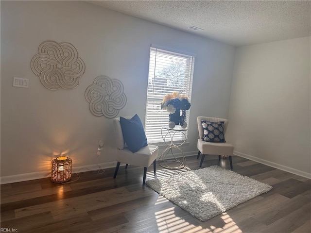 living area with a textured ceiling and dark hardwood / wood-style flooring