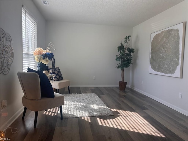 sitting room with dark wood-type flooring and a textured ceiling