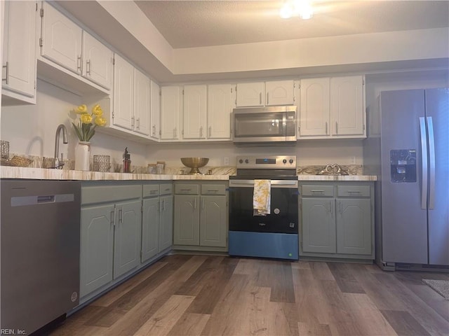 kitchen with stainless steel appliances, white cabinetry, sink, and dark hardwood / wood-style flooring