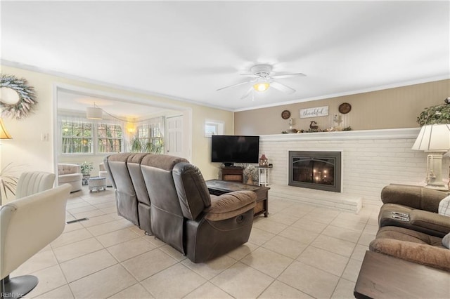 living room with ceiling fan, crown molding, light tile patterned floors, and a fireplace