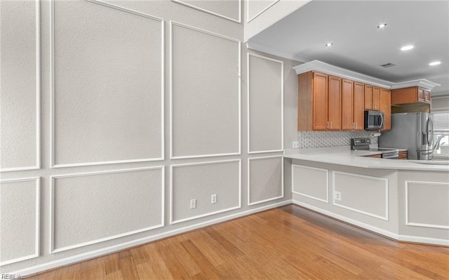 kitchen with backsplash, light hardwood / wood-style flooring, and appliances with stainless steel finishes