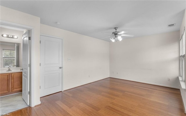 empty room with ceiling fan and light hardwood / wood-style flooring