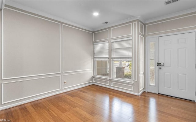 empty room with crown molding and light hardwood / wood-style flooring