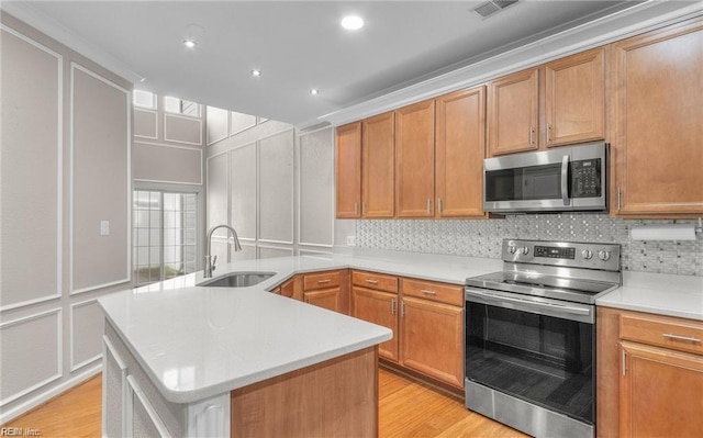 kitchen with sink, a kitchen island, stainless steel appliances, light hardwood / wood-style floors, and decorative backsplash