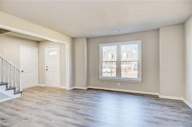 entrance foyer with light hardwood / wood-style flooring and a textured ceiling