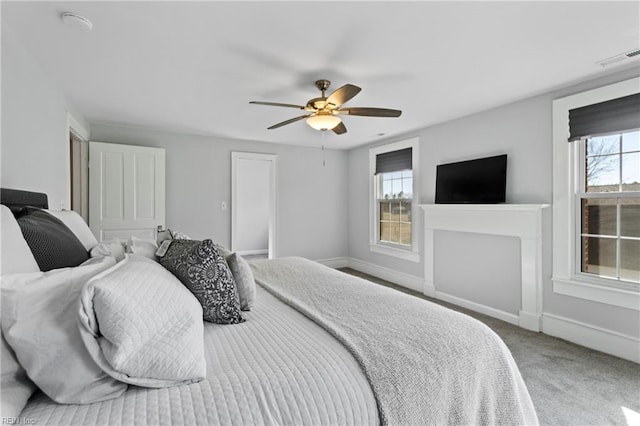 bedroom featuring ceiling fan, a fireplace, and carpet floors