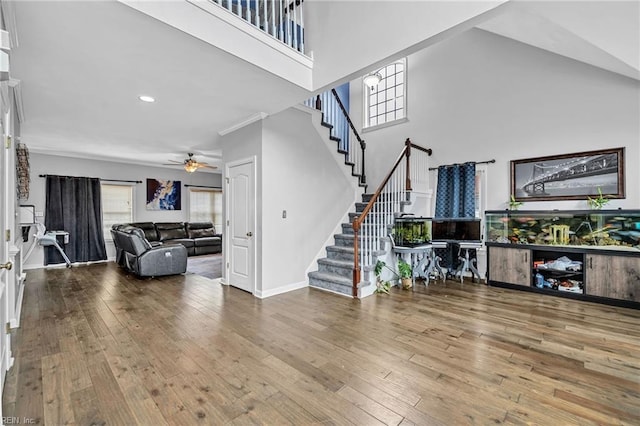 living room with ceiling fan, a towering ceiling, hardwood / wood-style floors, and a wealth of natural light