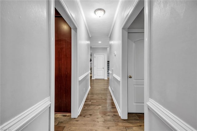 corridor with ornamental molding and light hardwood / wood-style floors