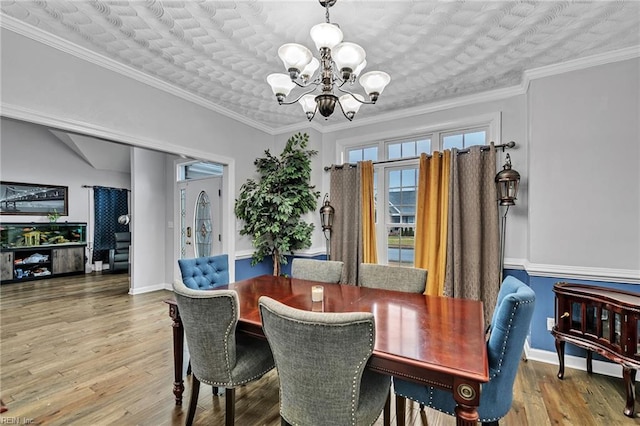 dining area with a notable chandelier, crown molding, and wood-type flooring