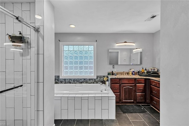 bathroom featuring vanity, tile patterned floors, and tiled bath