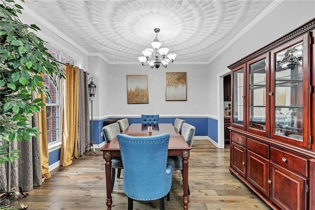 dining area with ornamental molding, a chandelier, and light hardwood / wood-style floors