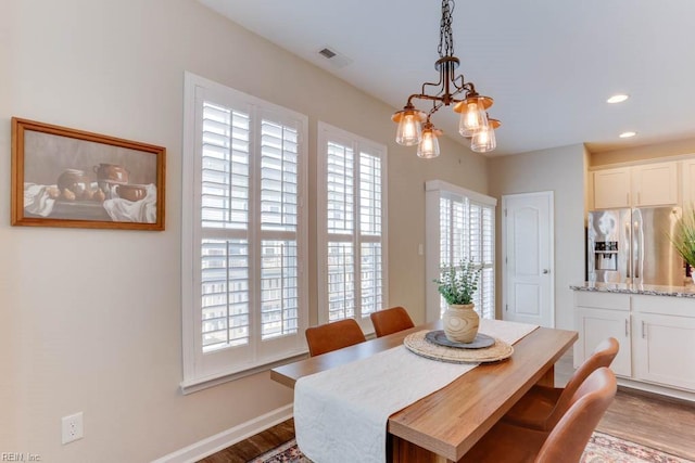 dining area featuring a healthy amount of sunlight, a chandelier, and light wood-type flooring