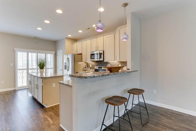 kitchen featuring a kitchen island, decorative light fixtures, tasteful backsplash, light stone counters, and stainless steel appliances