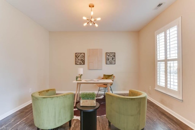 sitting room with a notable chandelier, dark wood-type flooring, and a healthy amount of sunlight