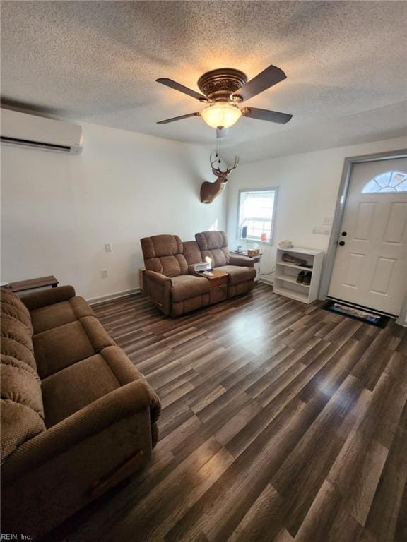 living area with an AC wall unit, dark wood finished floors, a textured ceiling, and ceiling fan