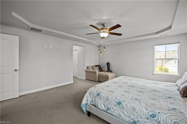 carpeted bedroom with a raised ceiling and ceiling fan