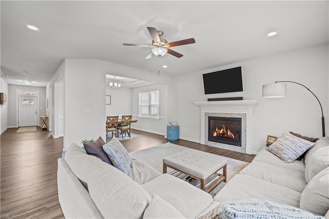 living room featuring ceiling fan with notable chandelier and dark hardwood / wood-style flooring